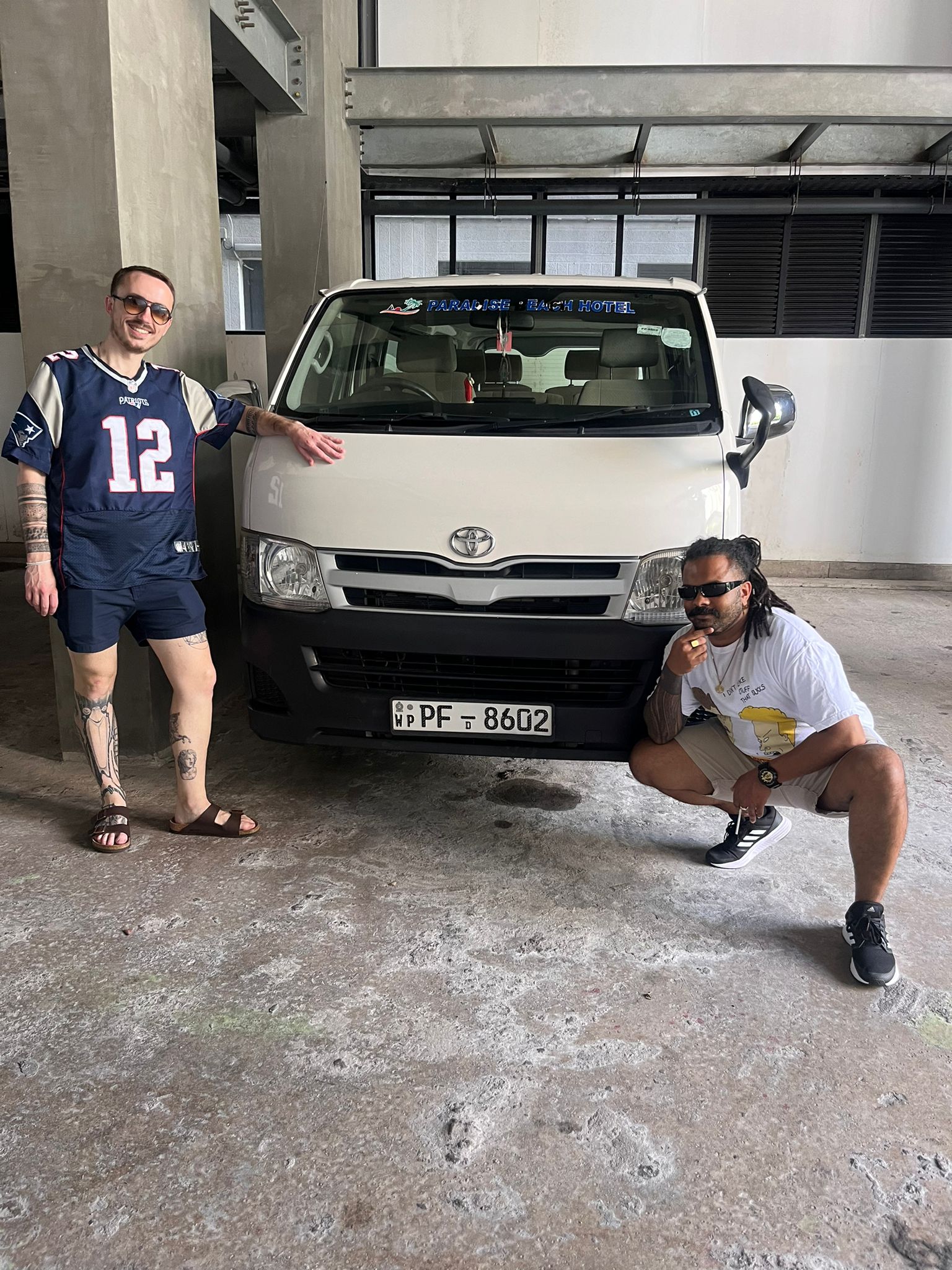 Two tourists posing with a rental van in a garage in Sri lanka 